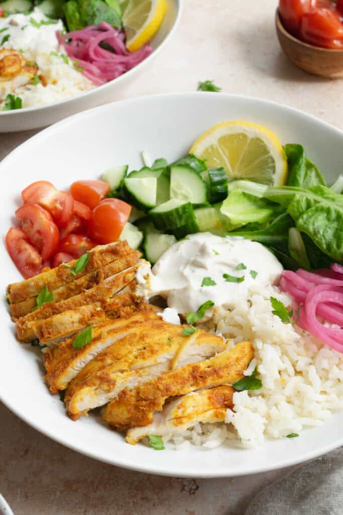 chicken shawarma bowls with rice, tomato, cucumber, lettuce, rice, pickled red onion.