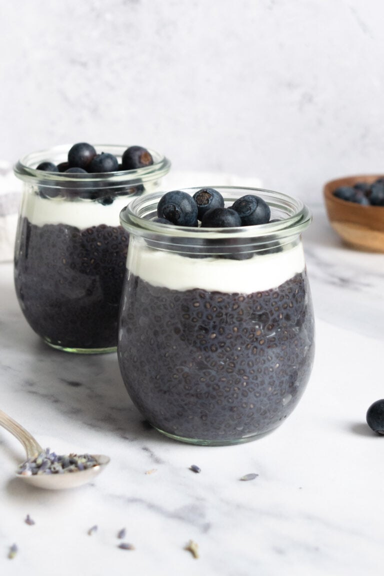 jars of lavender blueberry chia pudding topped with yogurt and blueberries.