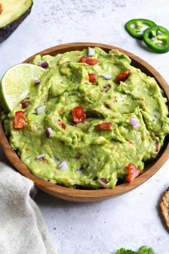 a bowl of guacamole with a lime wedge.