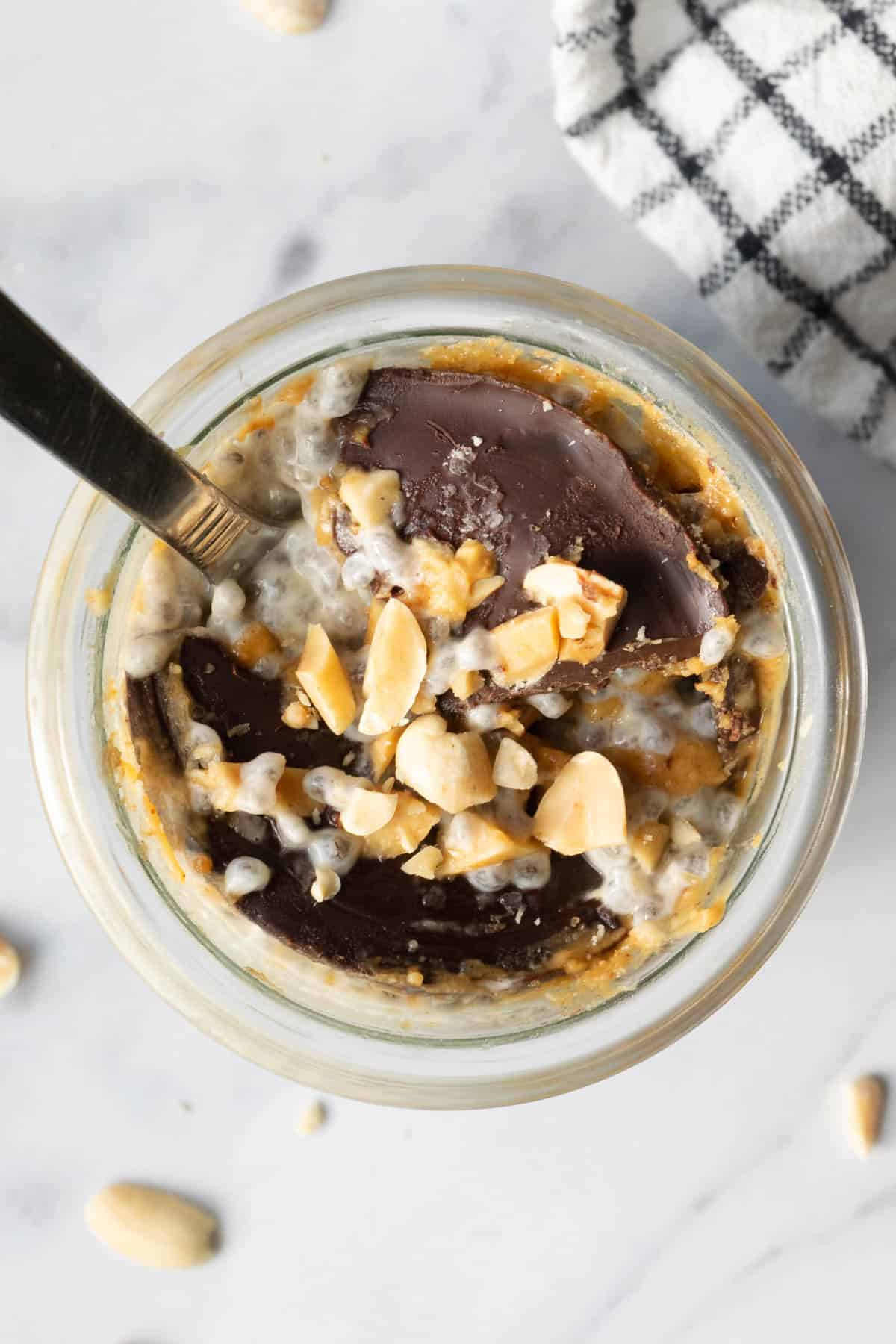 the top view of a jar of peanut butter chia pudding with a cracked chocolate shell.