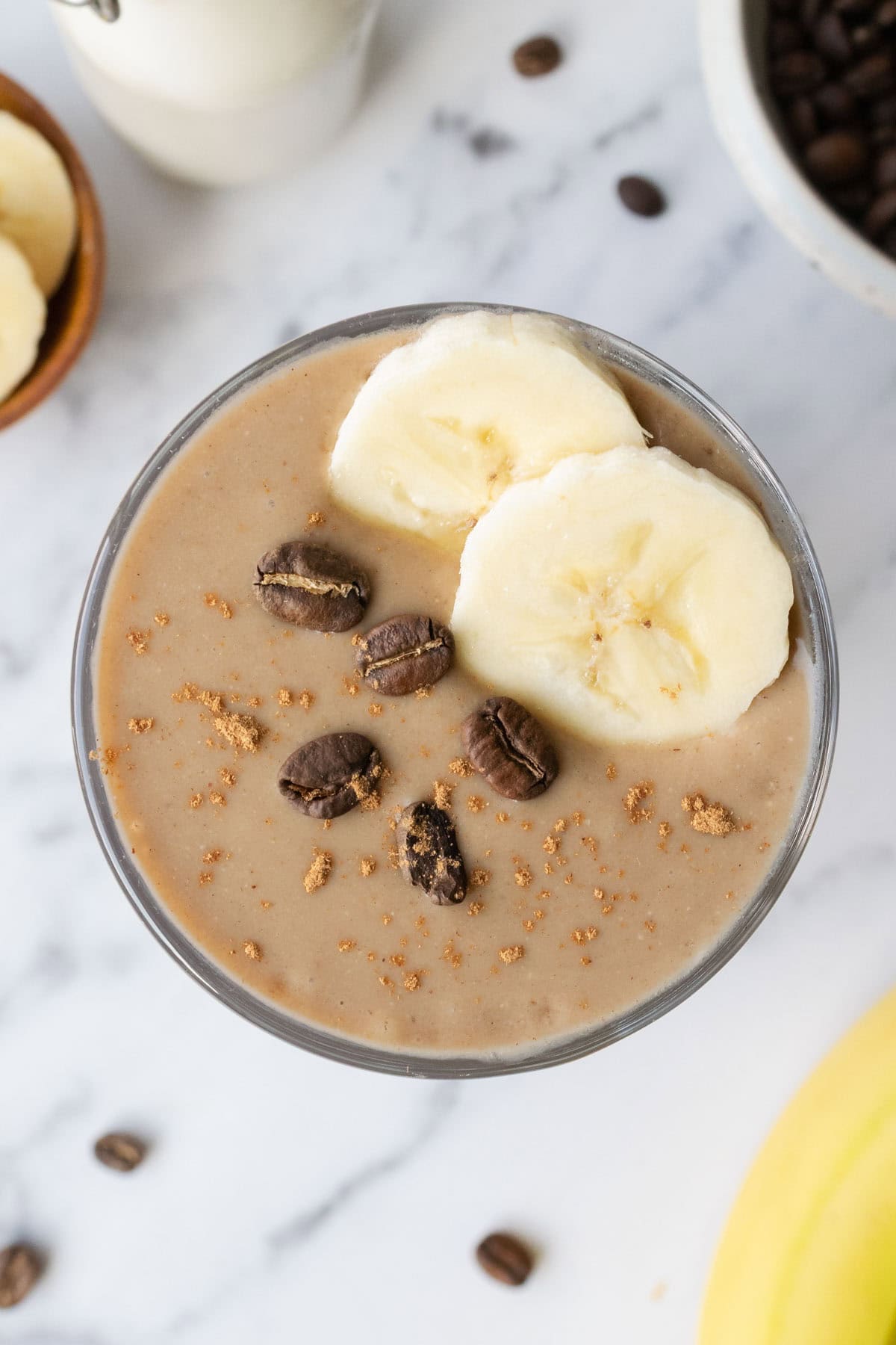 top view of a banana coffee smoothie topped with banana slices and coffee beans.