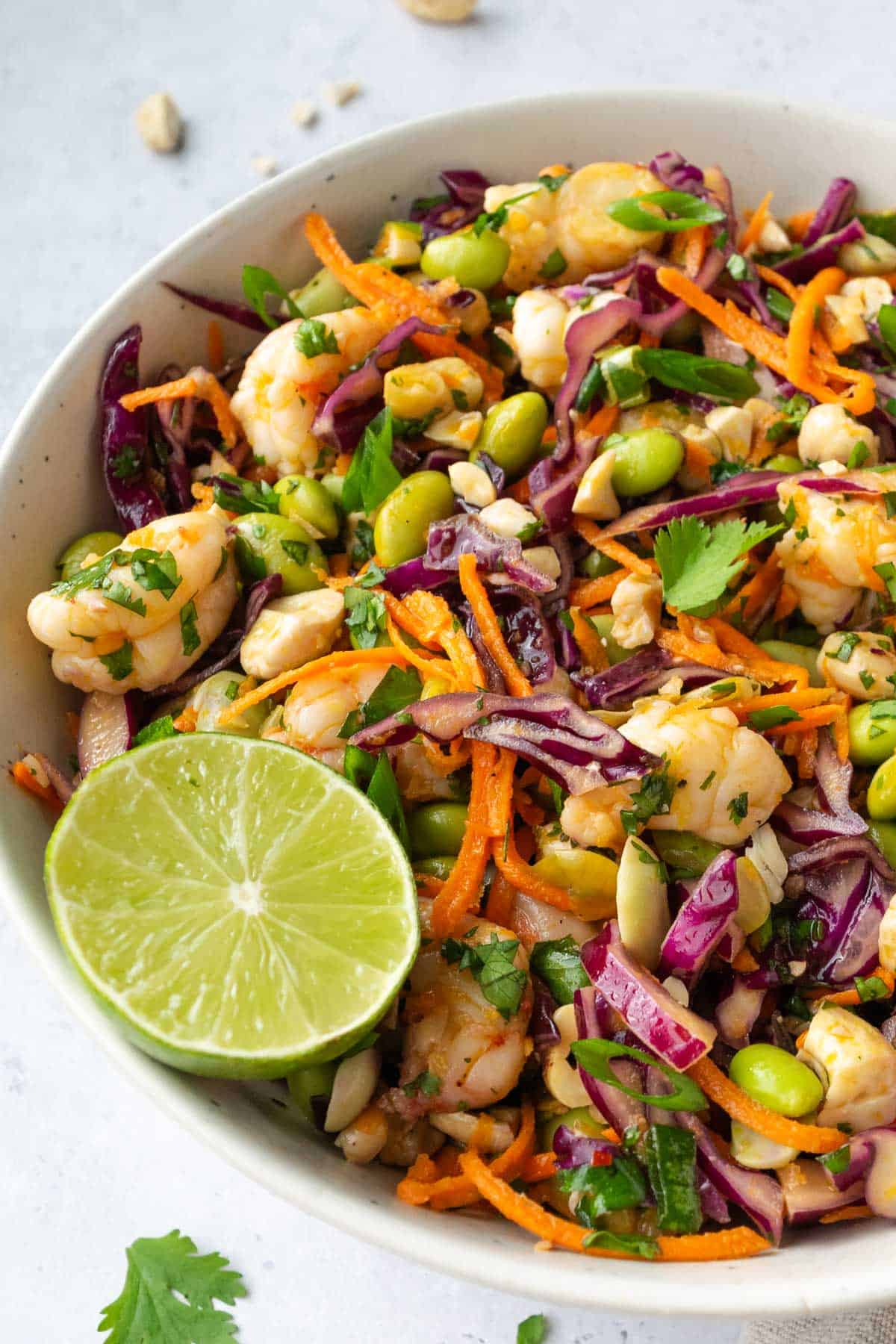 shrimp edamame salad in a white bowl topped with a cut lime.